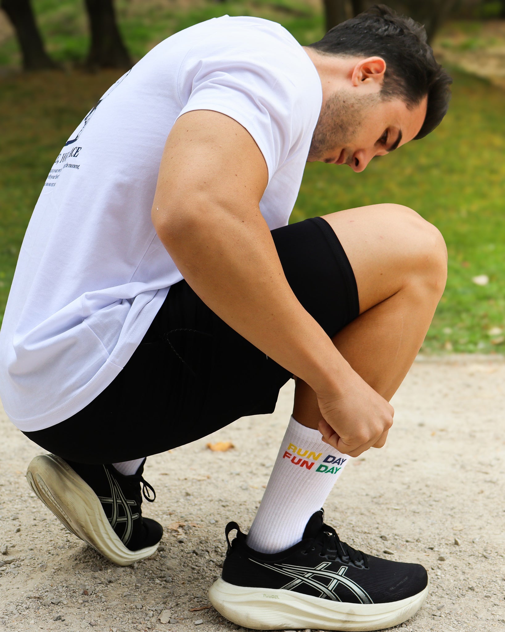 Persona ajustando los calcetines RUN DAY FUN DAY de Färgen antes de salir a correr, con fondo de parque