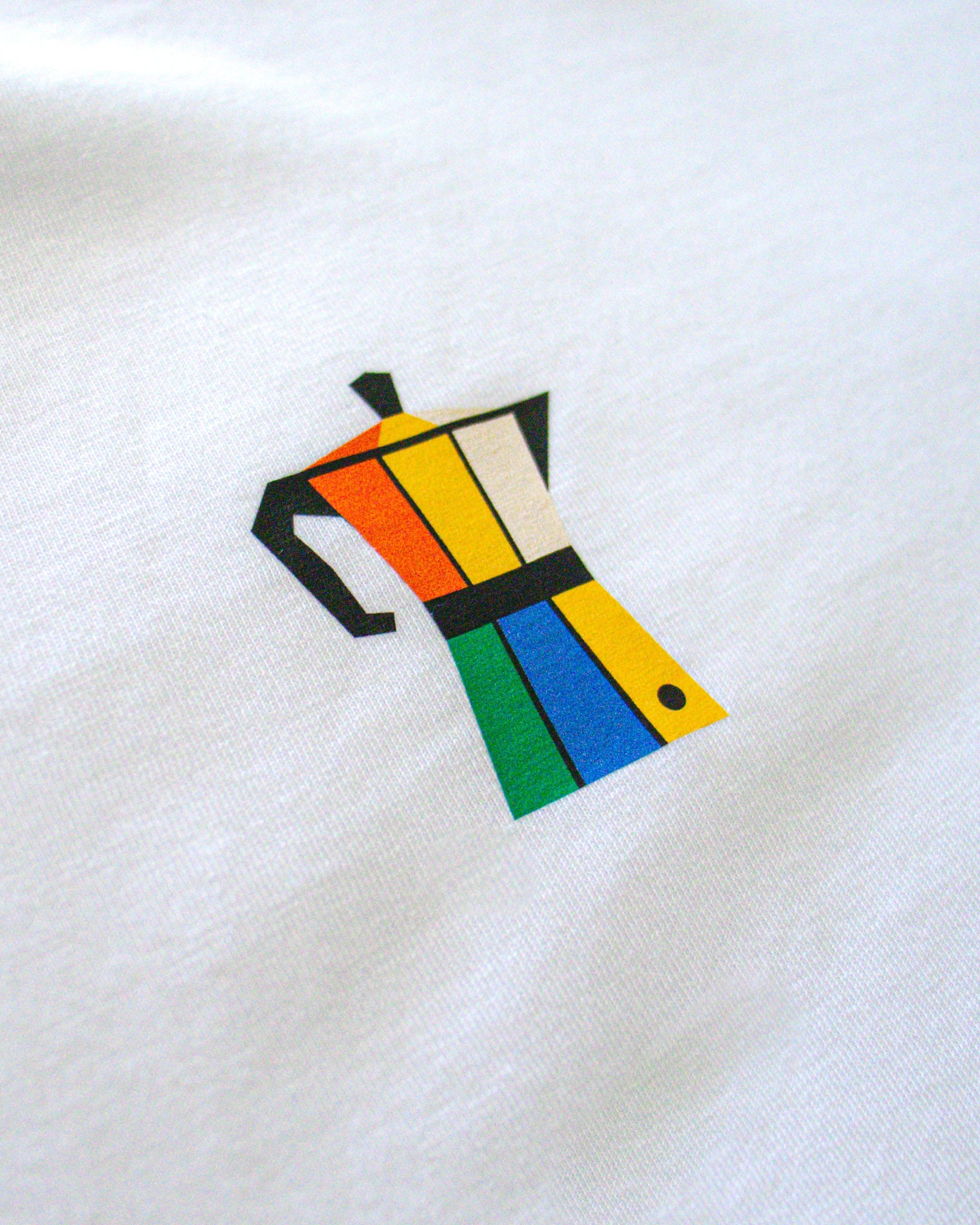 Detalle del diseño de cafetera italiana de colores en el pecho de la camiseta Färgen Il Caffè di Casa. Estilo Bauhaus