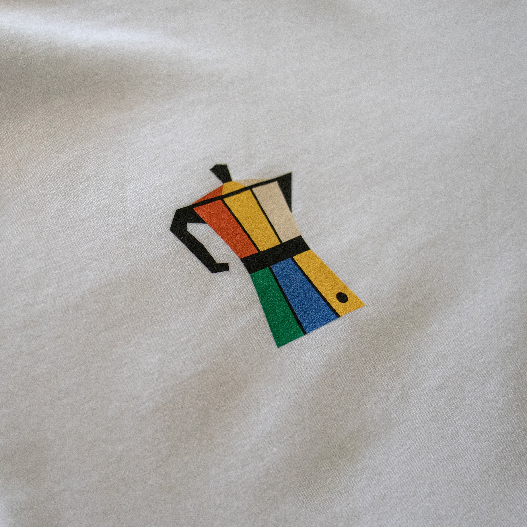 Detalle del diseño de cafetera italiana de colores en el pecho de la camiseta Färgen Il Caffè di Casa. Estilo Bauhaus