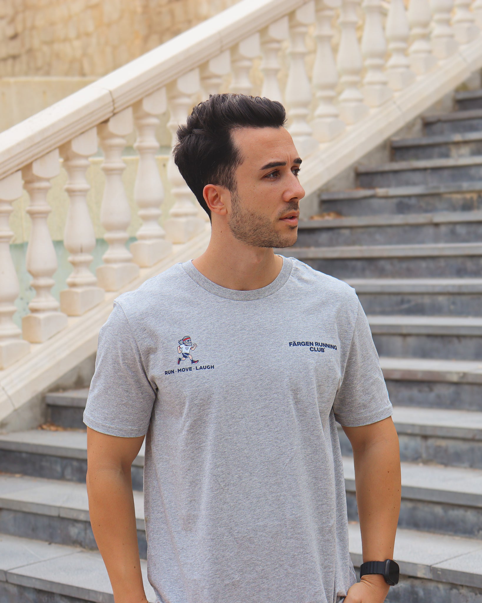 Hombre con camiseta gris Färgen Running Club mostrando el diseño frontal con logotipo y lema RUN MOVE LAUGH.