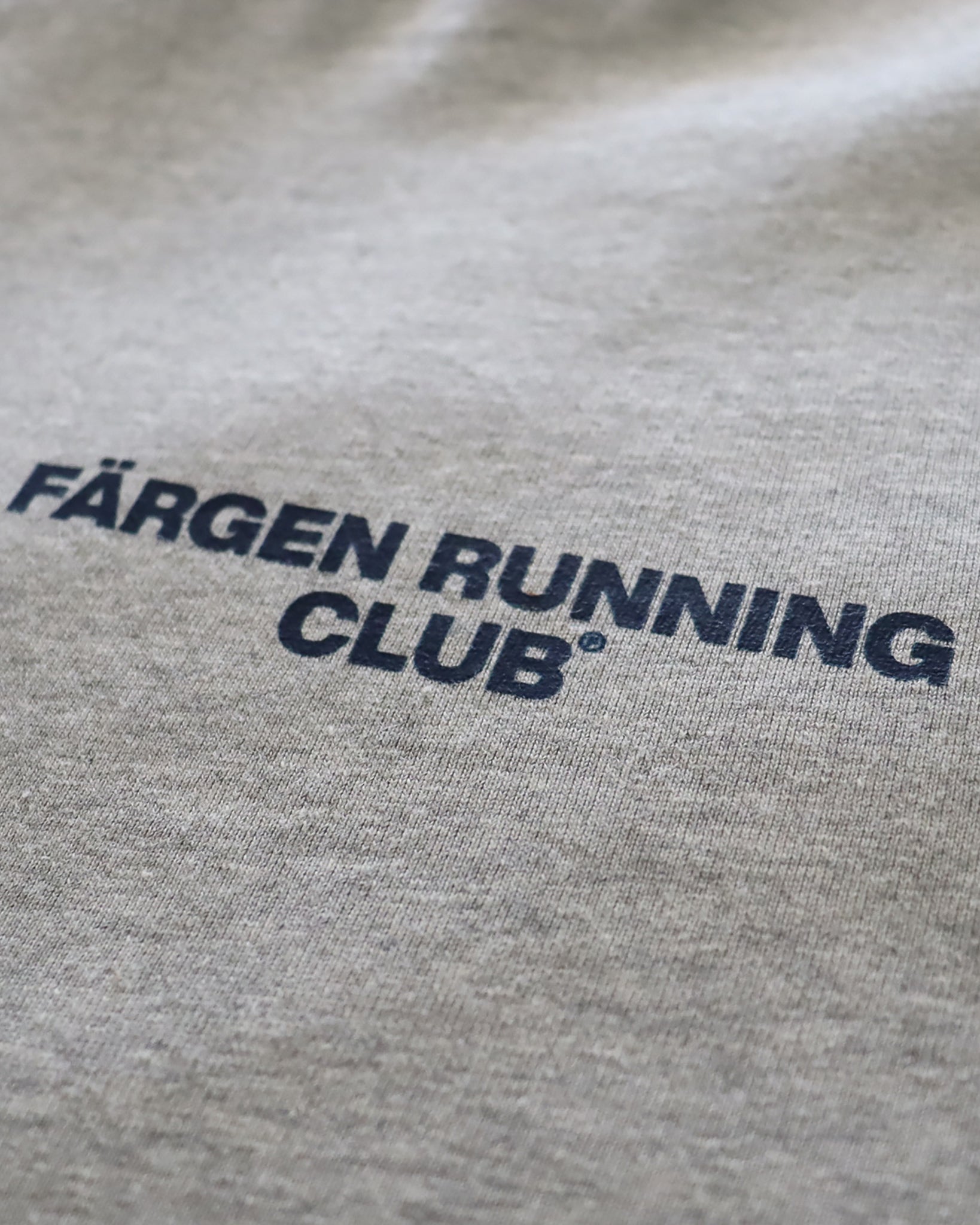 Detalle del logotipo Färgen Running Club estampado en el pecho de la camiseta gris.