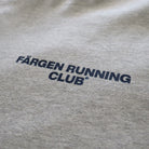 Detalle del logotipo Färgen Running Club estampado en el pecho de la camiseta gris.