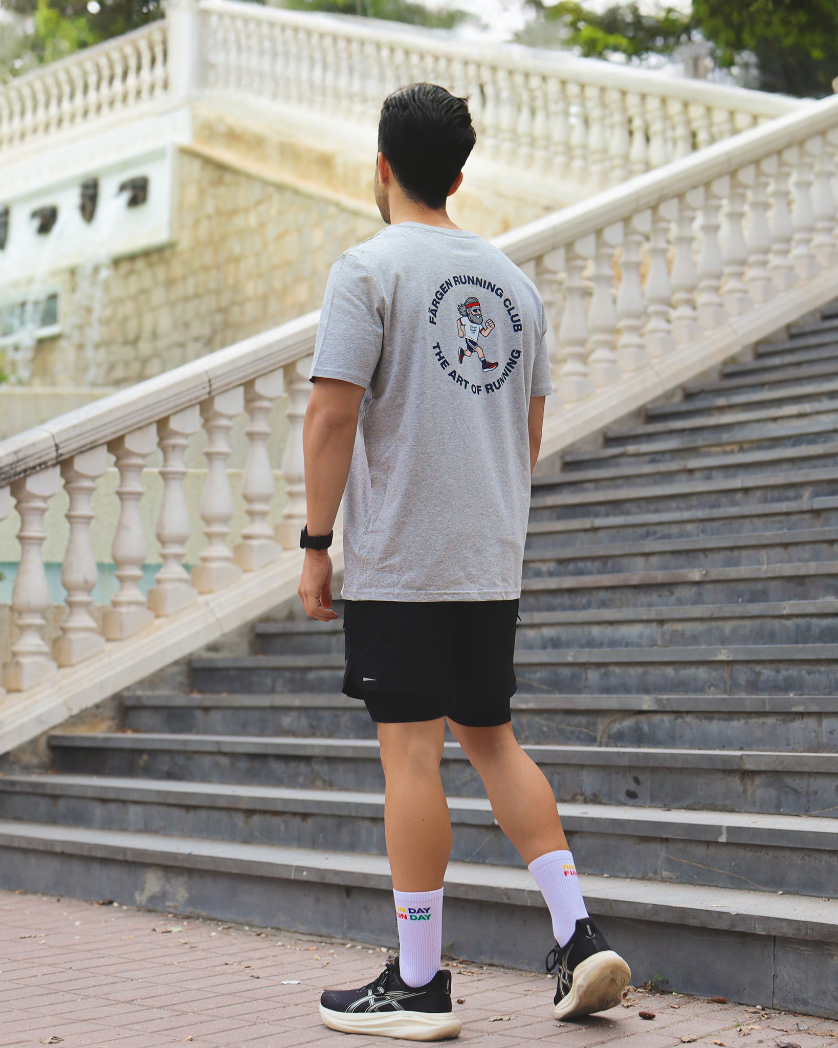 Hombre con camiseta gris Färgen Running Club caminando, mostrando el diseño trasero The Art of Running