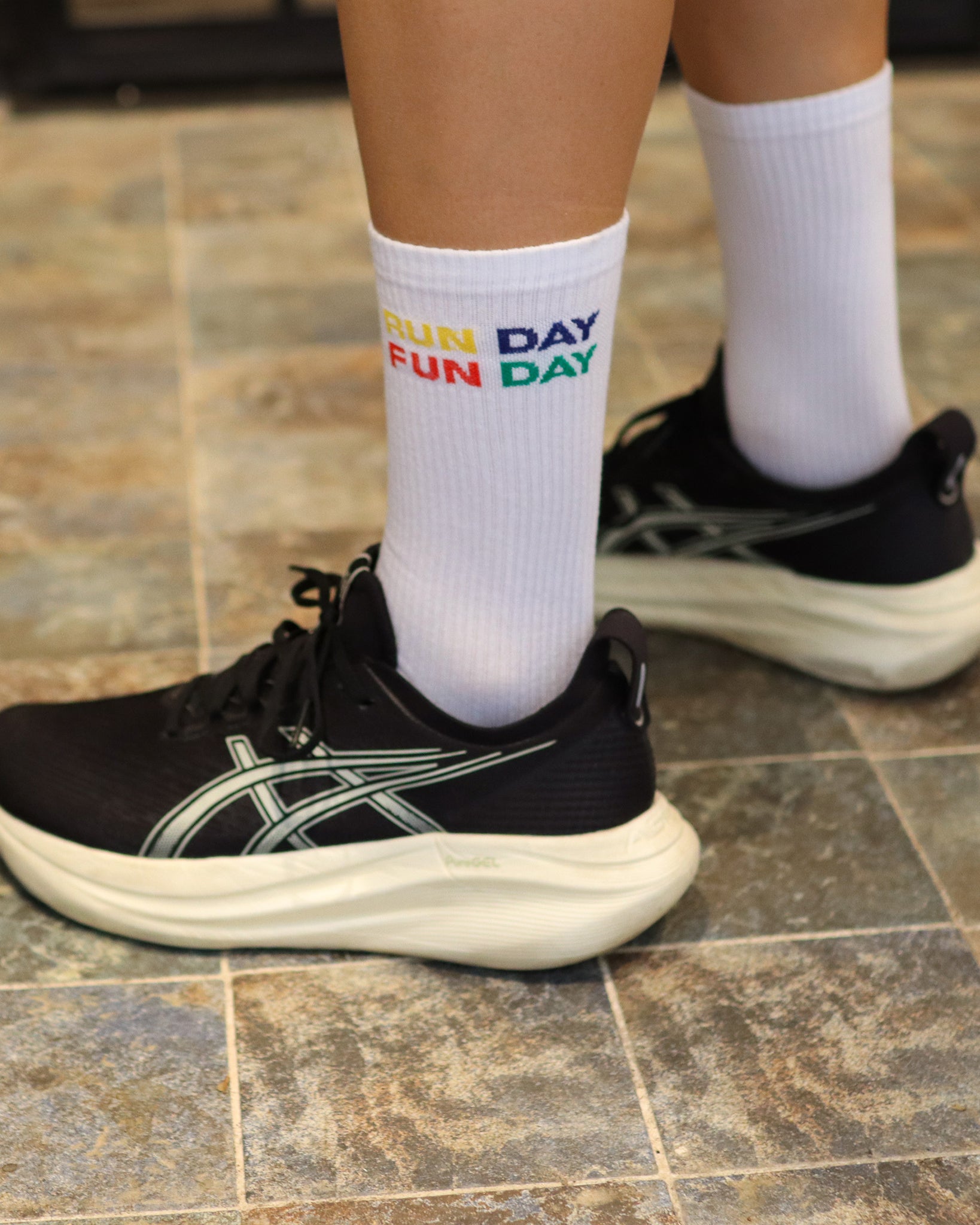 Primer plano de calcetines RUN DAY FUN DAY de Färgen en color blanco con bordado multicolor, combinados con zapatillas de running