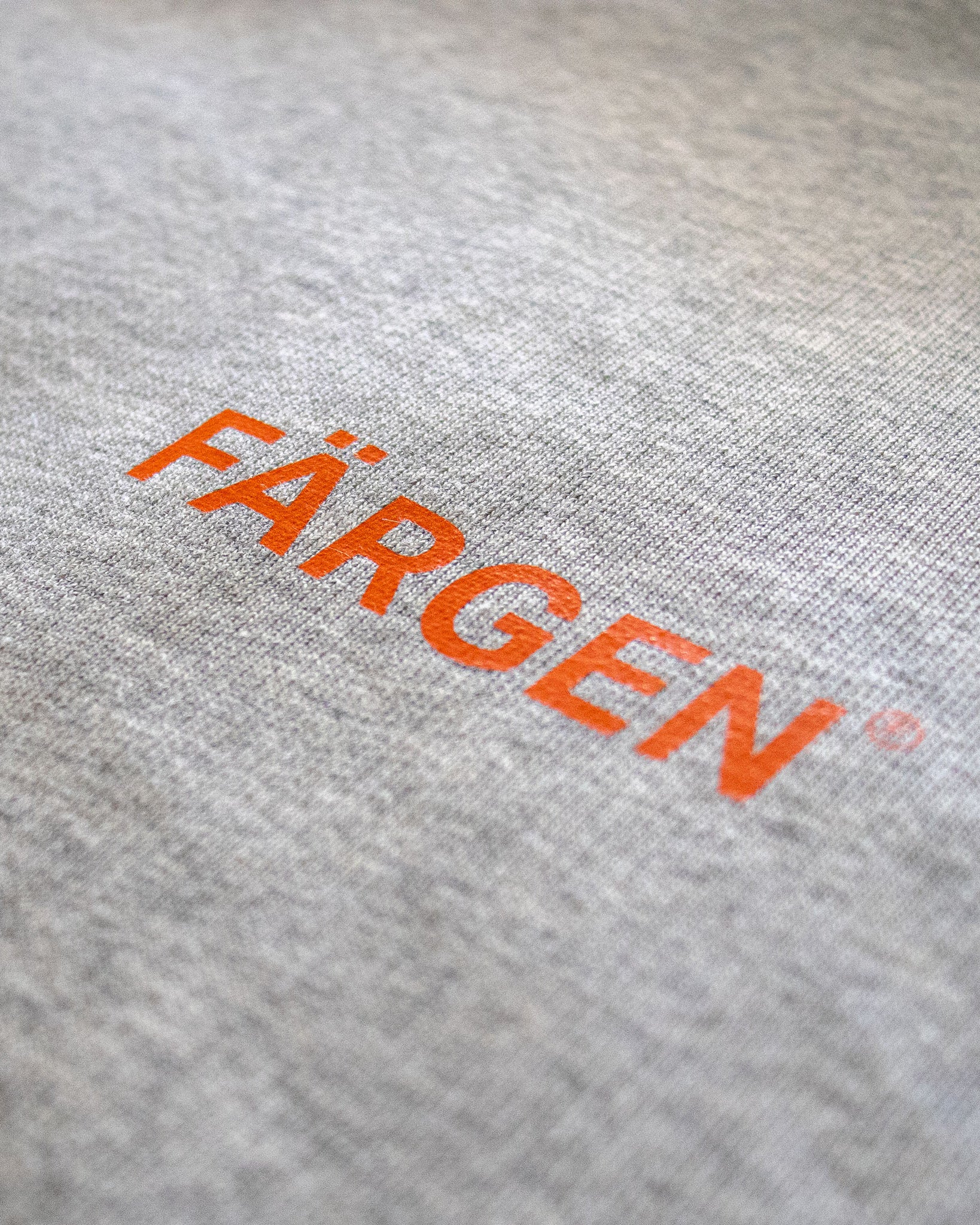 Detalle del logotipo Färgen estampado en naranja sobre la sudadera gris Il Caffè di Casa.