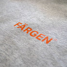 Detalle del logotipo Färgen estampado en naranja sobre la sudadera gris Il Caffè di Casa.