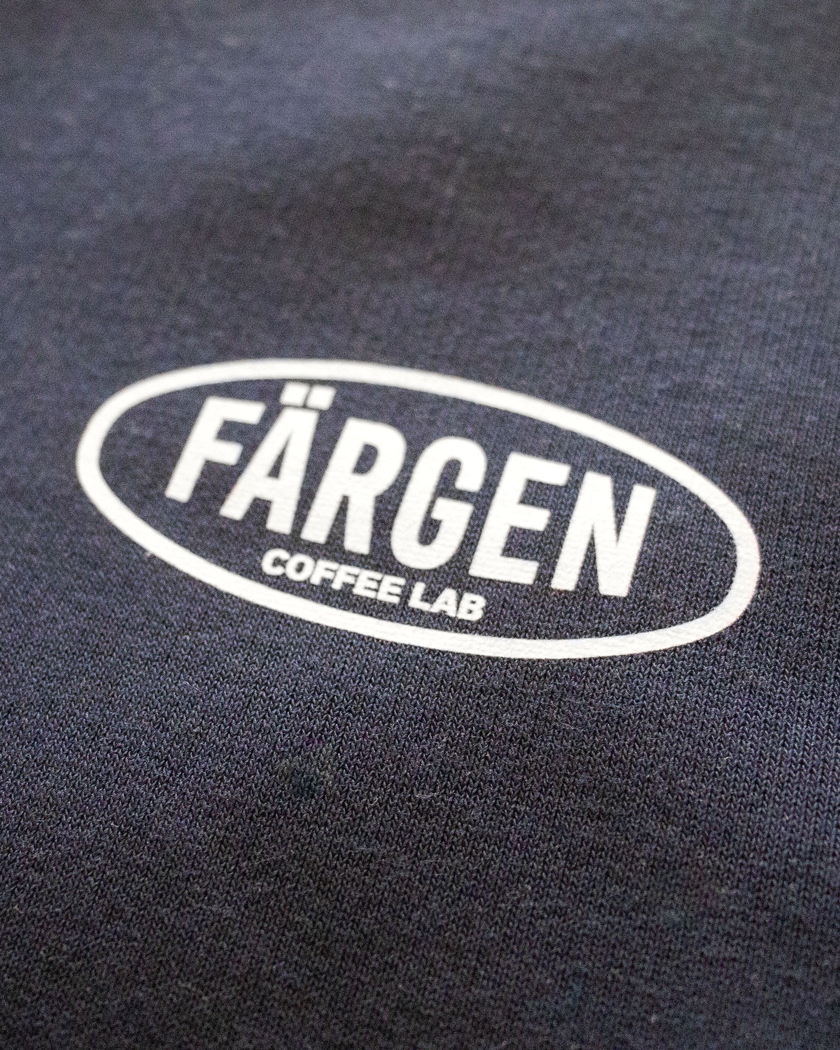 Detalle del logotipo Färgen Coffee Lab en blanco estampado en la sudadera azul marino The Coffee Maniacs Dept.