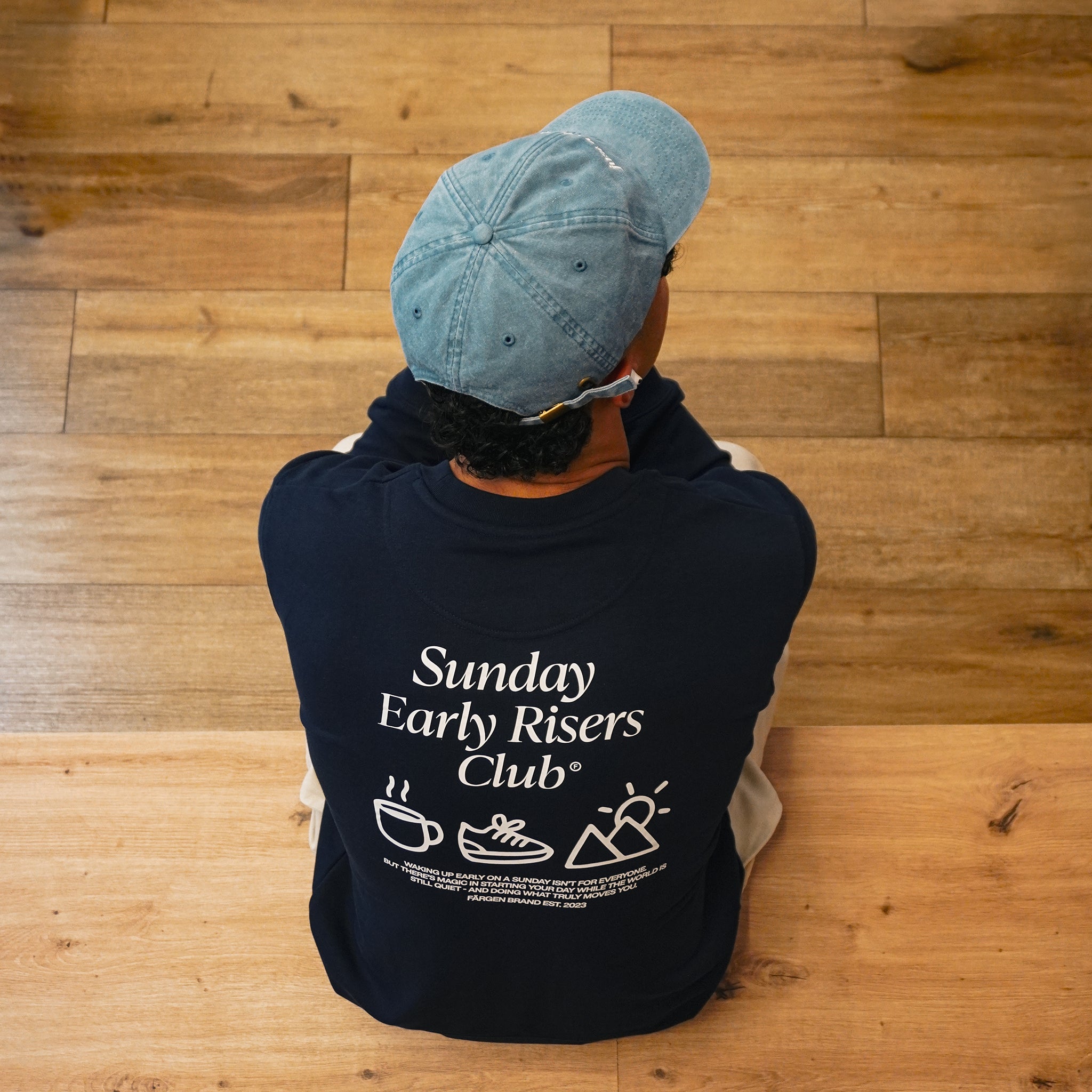 Sudadera Färgen Sunday Early Risers Club en exterior, estilo casual-outdoor para mañanas frescas en cafetería minimalista.