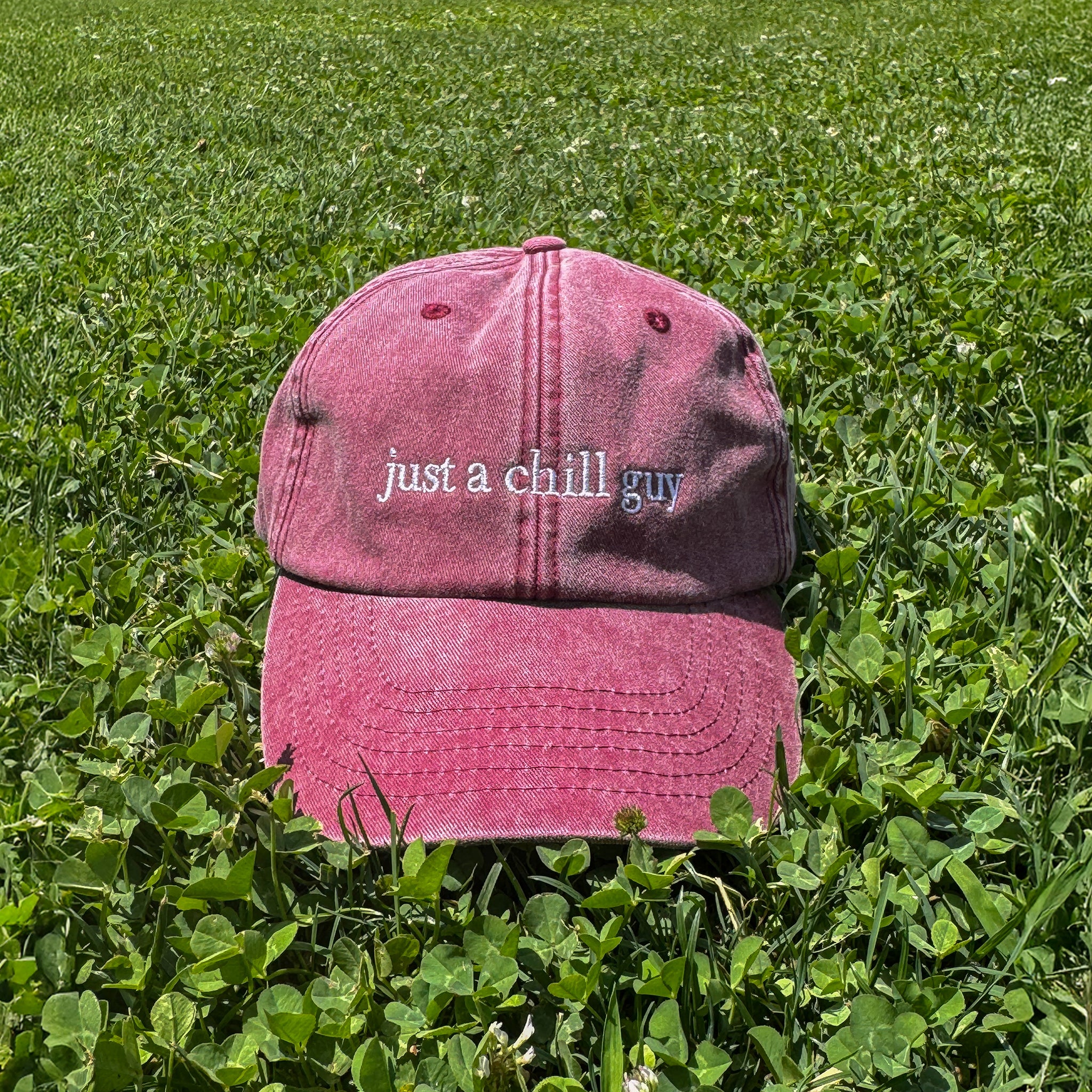 “Detalle del parche Just a Chill Guy en gorra Färgen, estética minimalista en cesped natural.
