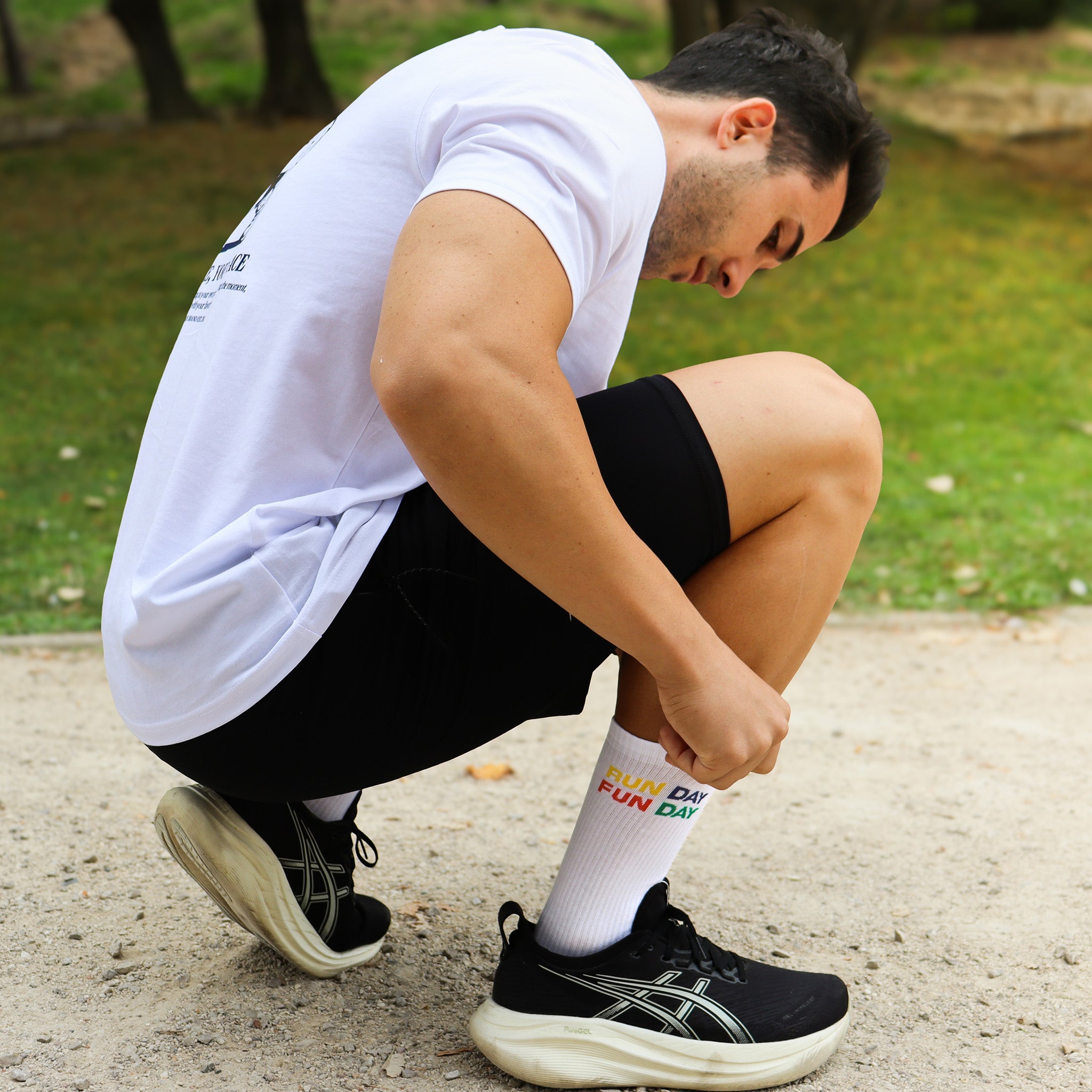 Persona ajustando los calcetines RUN DAY FUN DAY de Färgen antes de salir a correr, con fondo de parque
