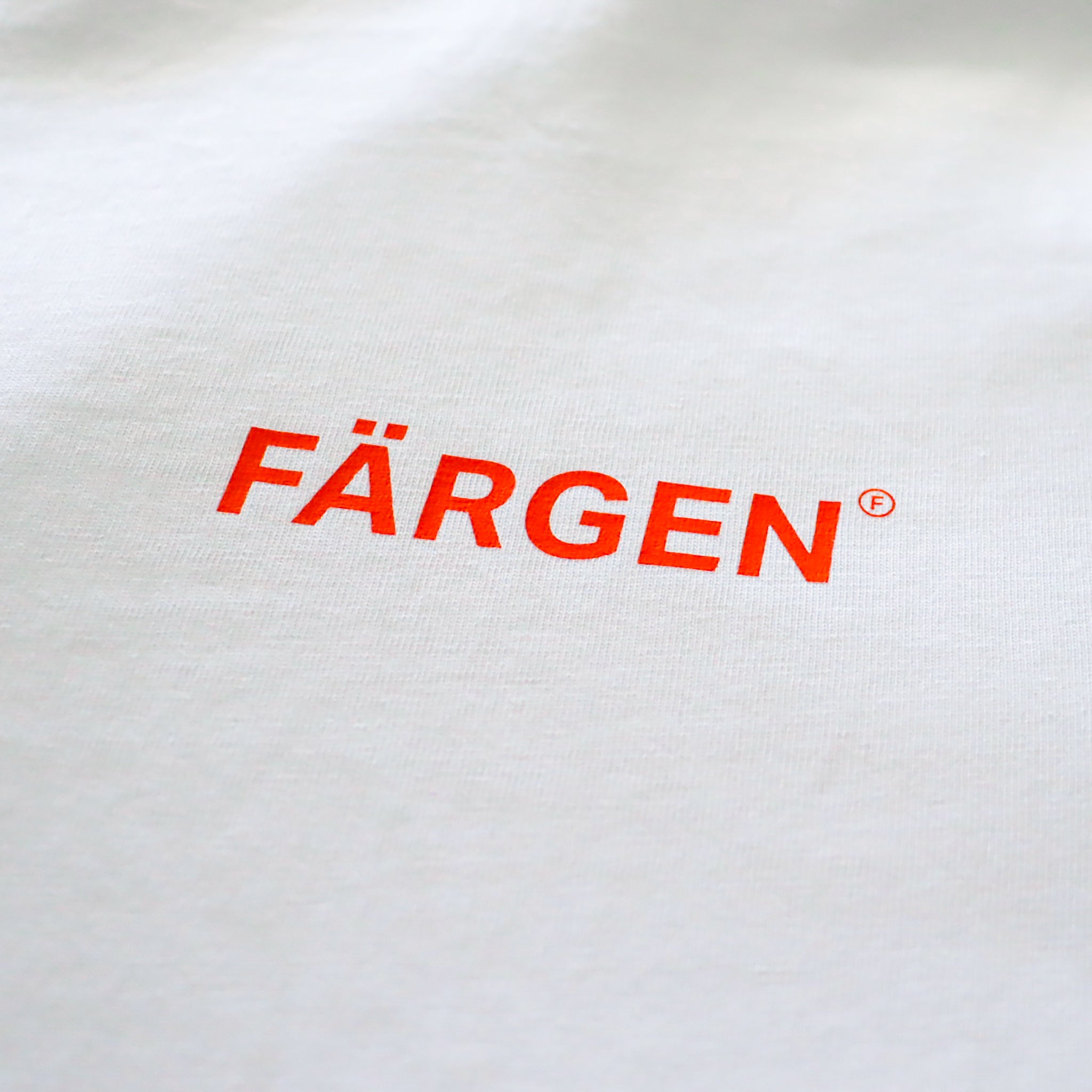 Detalle del logotipo Färgen en naranja estampado en el pecho de la camiseta Il Caffè di Casa.