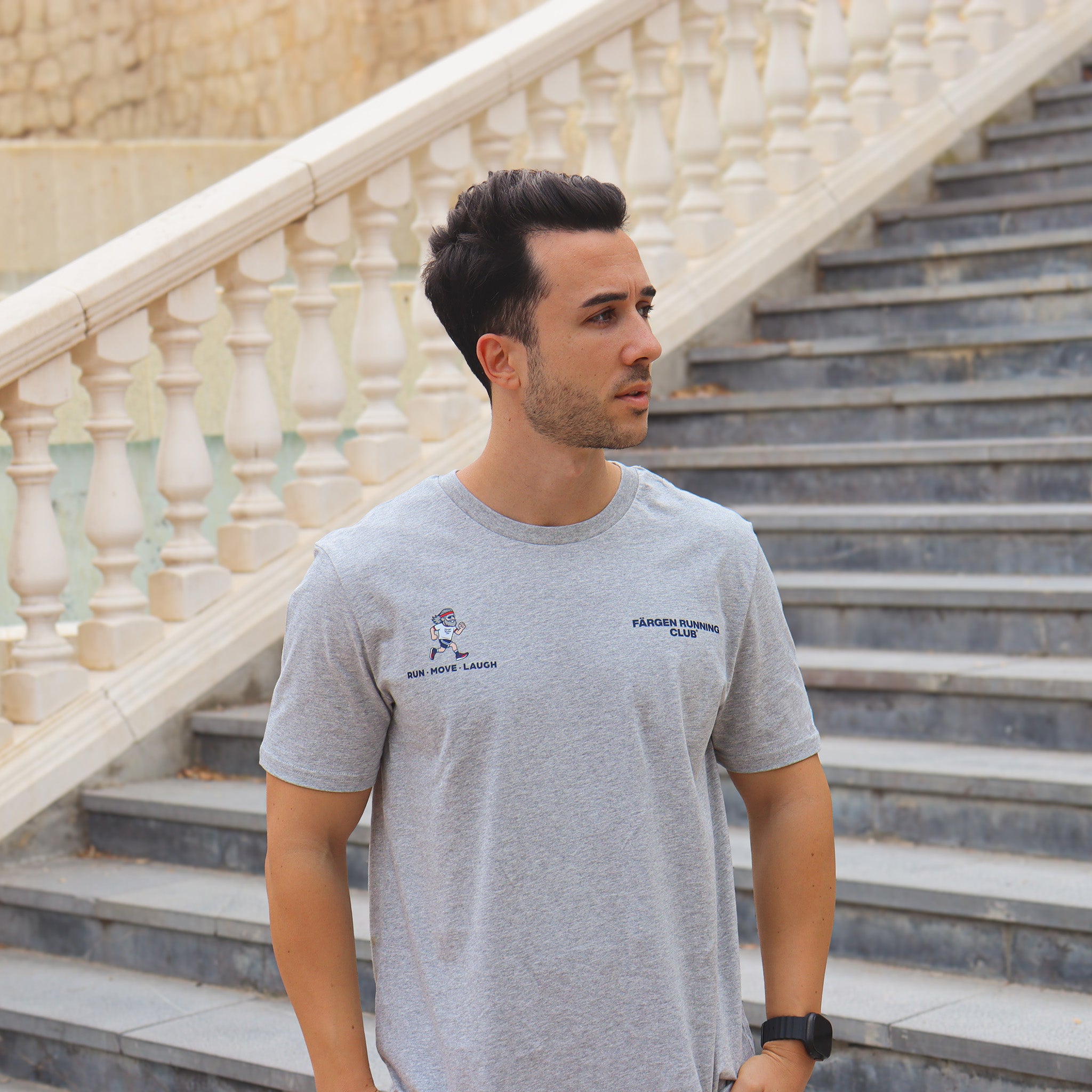 Hombre con camiseta gris Färgen Running Club mostrando el diseño frontal con logotipo y lema RUN MOVE LAUGH.