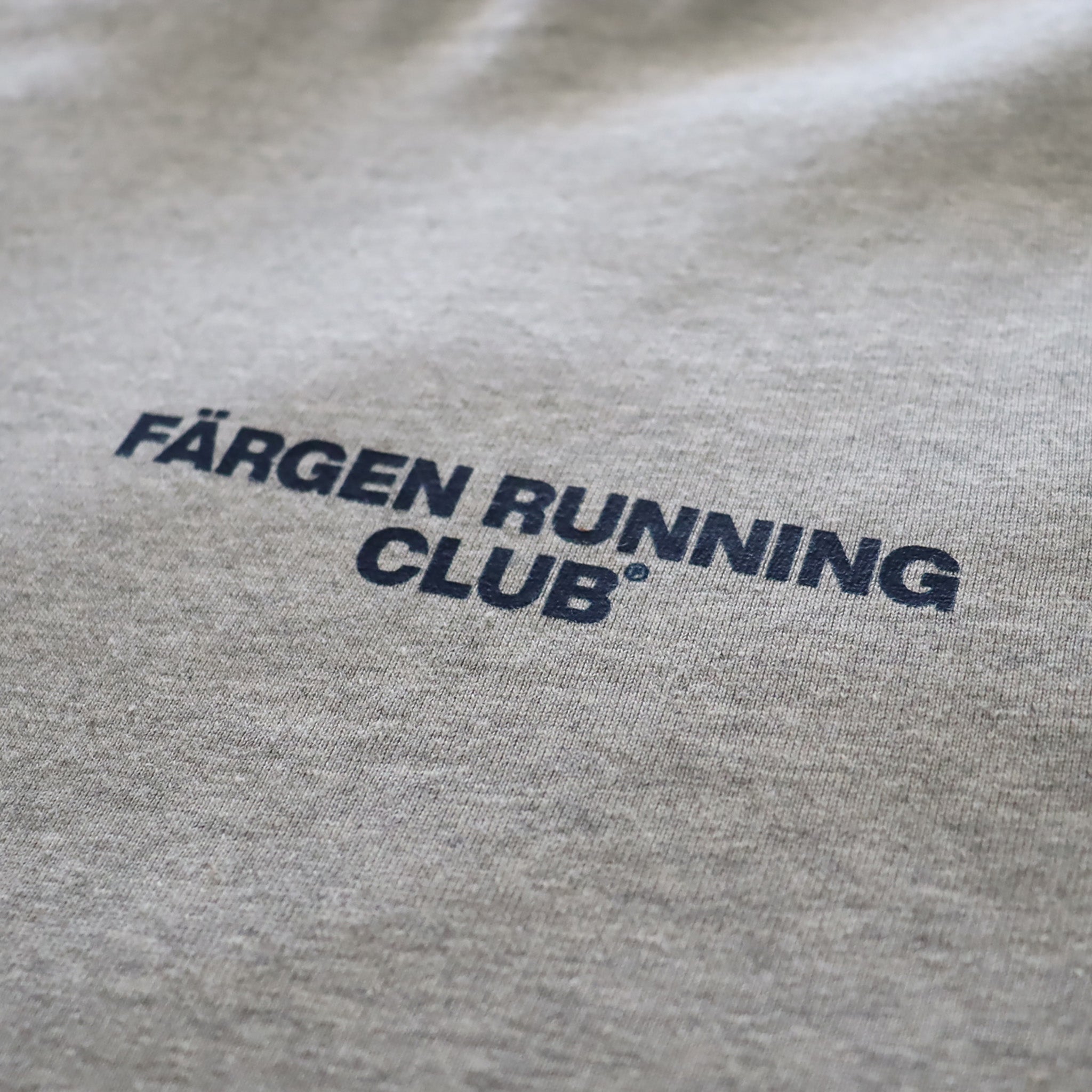 Detalle del logotipo Färgen Running Club estampado en el pecho de la camiseta gris.
