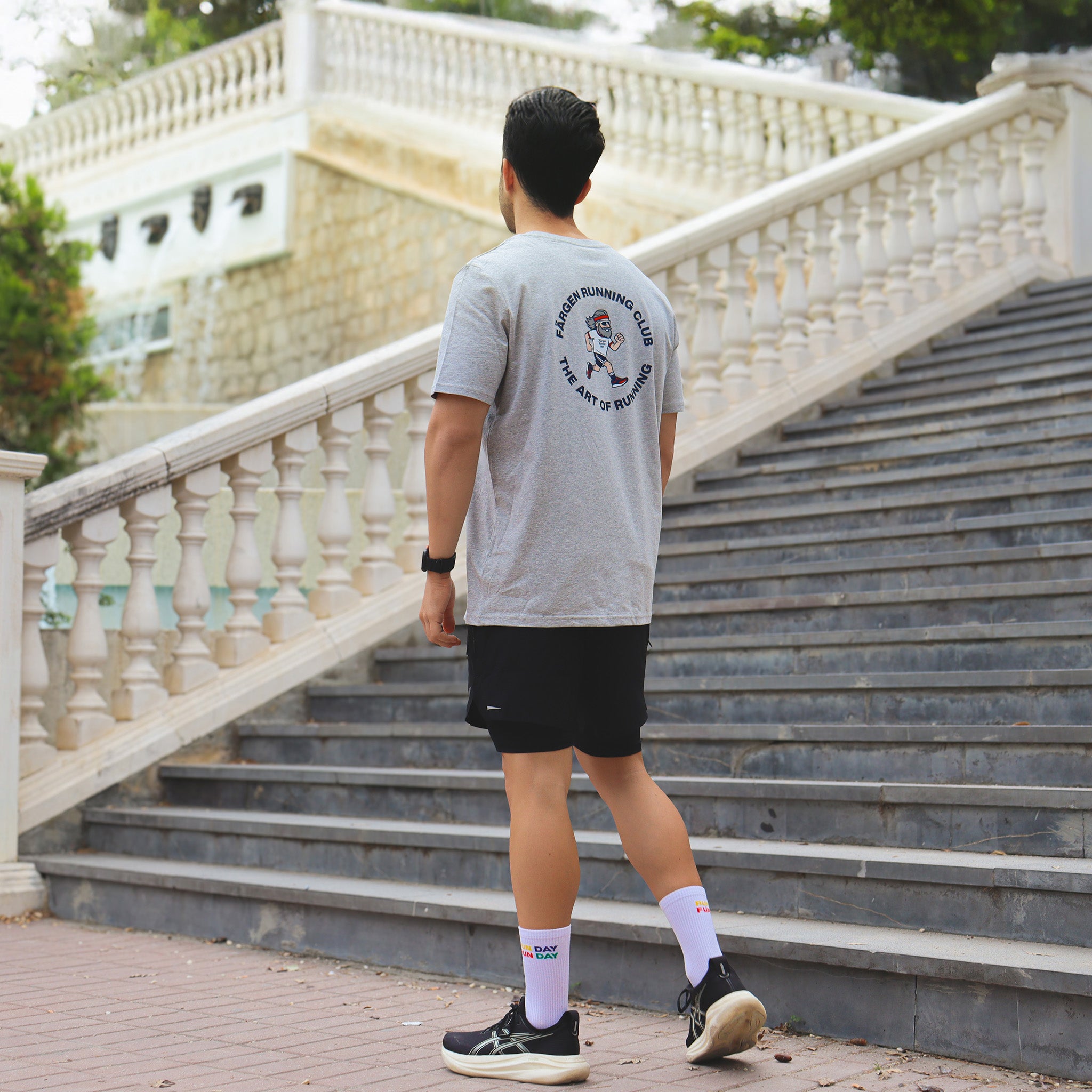 Hombre con camiseta gris Färgen Running Club caminando, mostrando el diseño trasero The Art of Running