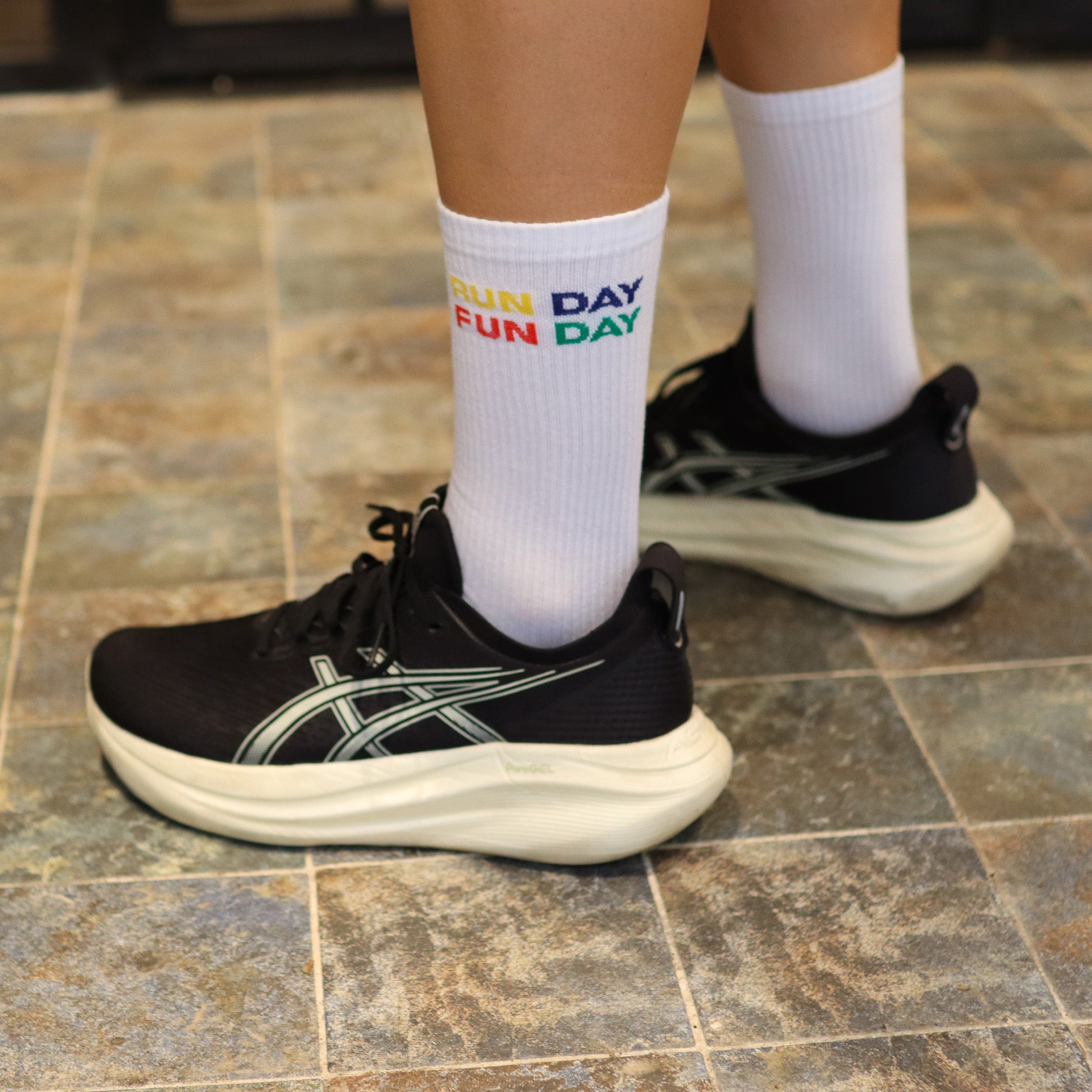 Primer plano de calcetines RUN DAY FUN DAY de Färgen en color blanco con bordado multicolor, combinados con zapatillas de running
