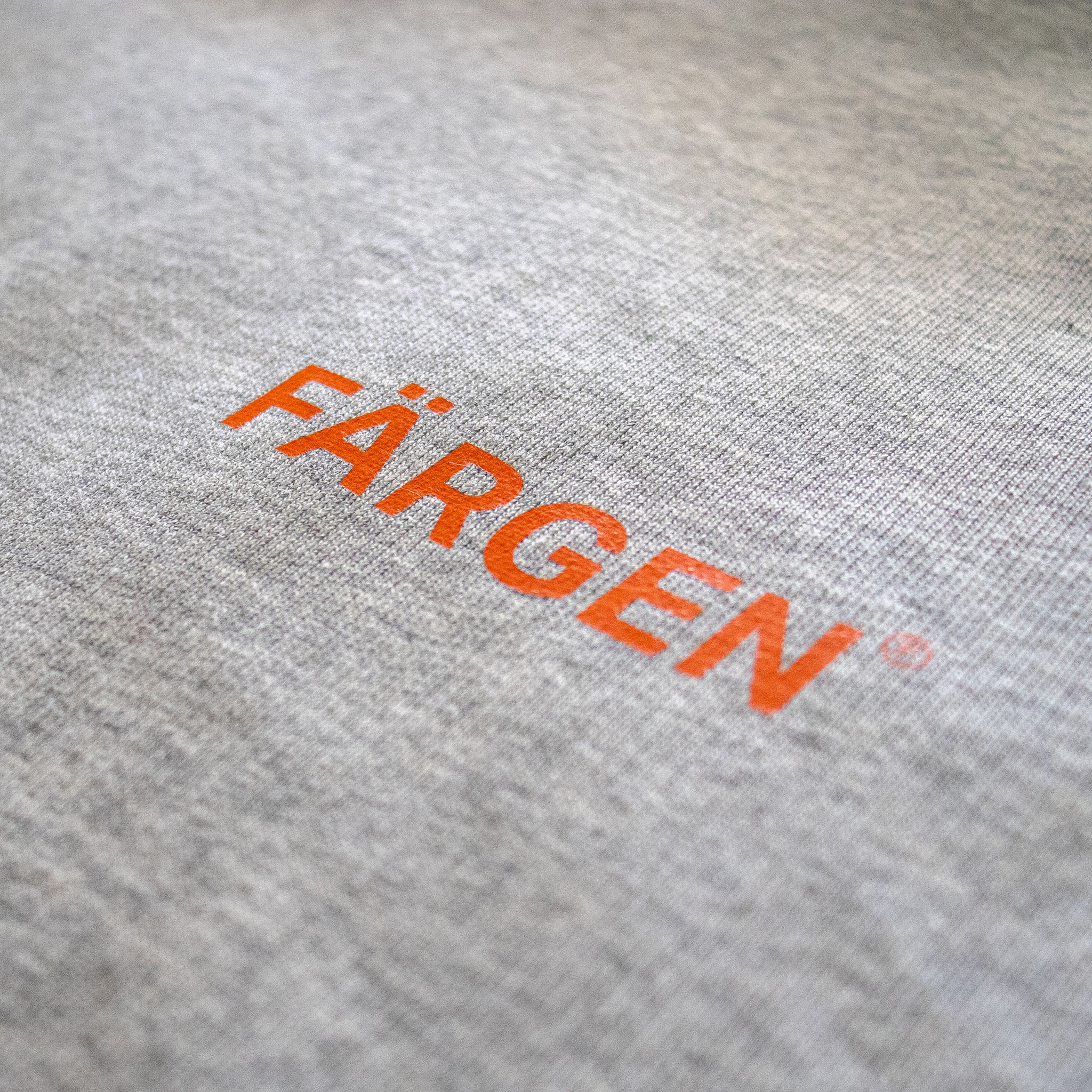 Detalle del logotipo Färgen estampado en naranja sobre la sudadera gris Il Caffè di Casa.