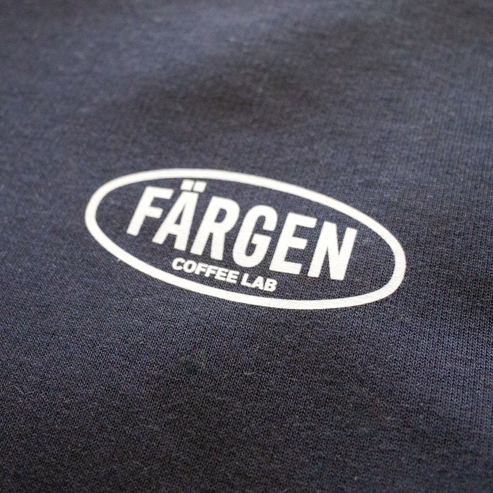 Detalle del logotipo Färgen Coffee Lab en blanco estampado en la sudadera azul marino The Coffee Maniacs Dept.
